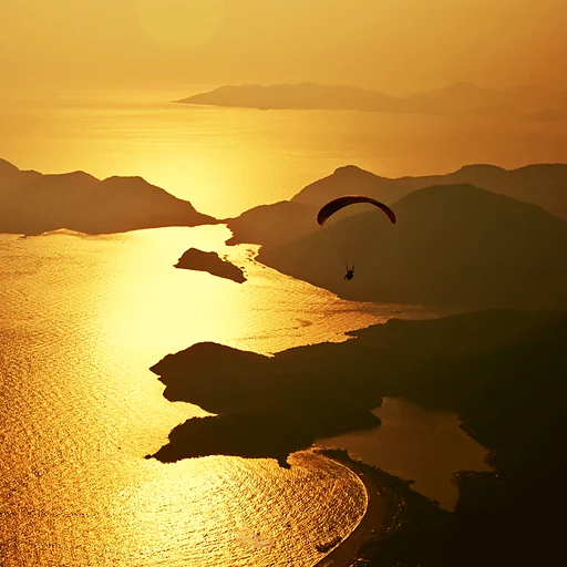 Ölüdeniz üzerinde gün batımında yamaç paraşütü